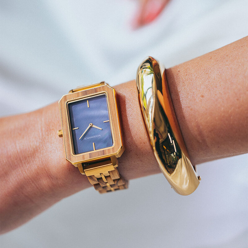 The Elegance Blue Pearl is crafted from olive wood and stainless steel, featuring a blue mother-of-pearl dial with brushed gold metal details.