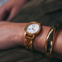 The Radiance Ivory Pearlworld is crafted from olive wood and stainless steel brushed gold, featuring a pearl white dial and brushed gold metal details.