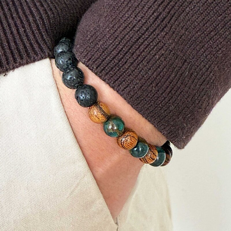 Made with rosewood beads, volcanic beads, dark green natural stone beads, and a matte black brass closure. Adjustable, with 8mm beads to fit most wrist sizes.