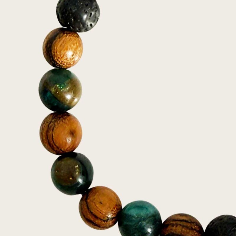 Made with rosewood beads, volcanic beads, dark green natural stone beads, and a matte black brass closure. Adjustable, with 8mm beads to fit most wrist sizes.