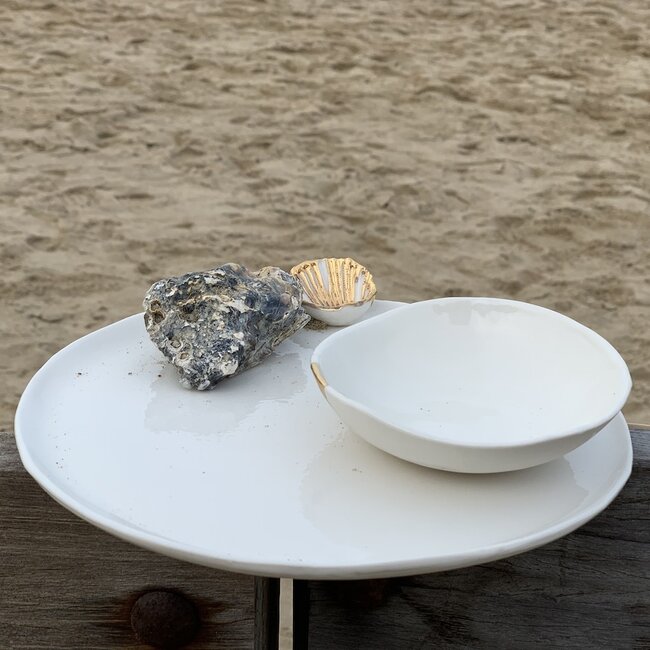 Handgemaakt bordje in witte porselein met een blinkende transparante glazuur afgewerkt met een schelpje en een gouden speelse touch