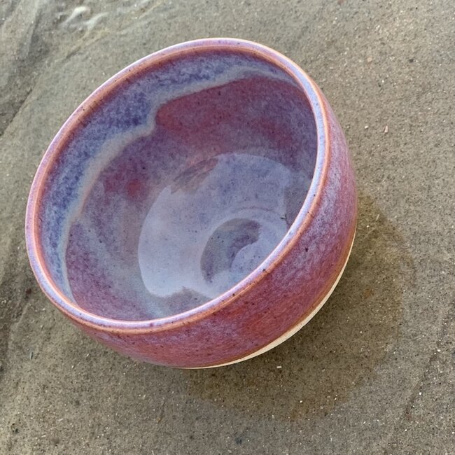 With the turntable handmade bowl of Pyerite clay with a beautiful Floating magenta roos high-firing glaze.