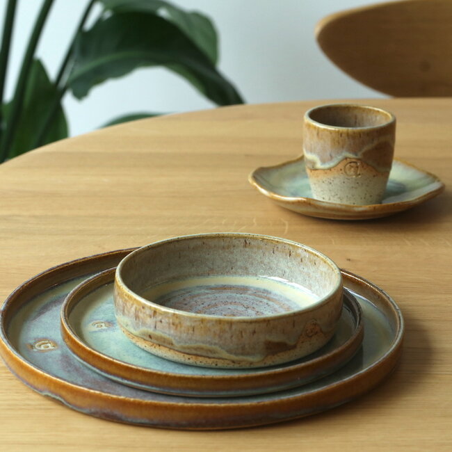 L’assiette fait avec les mains en argile beige et son magnifique glaçage à claire mosterd.