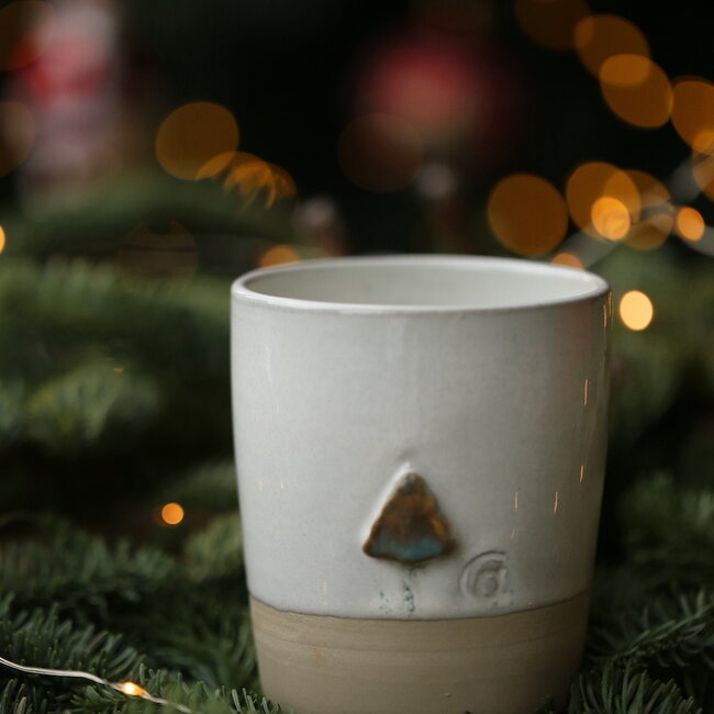 White handmade ceramic tea cup from the “White Christmas tree” service with a mint-colored christmas tree