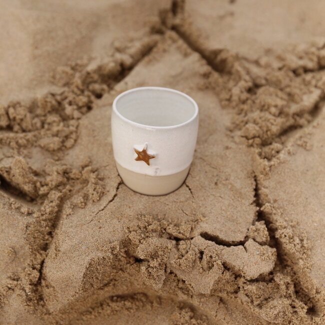Wit handgemaakte keramische tas van het servies “White Star" met een mosterdkleurige zeester