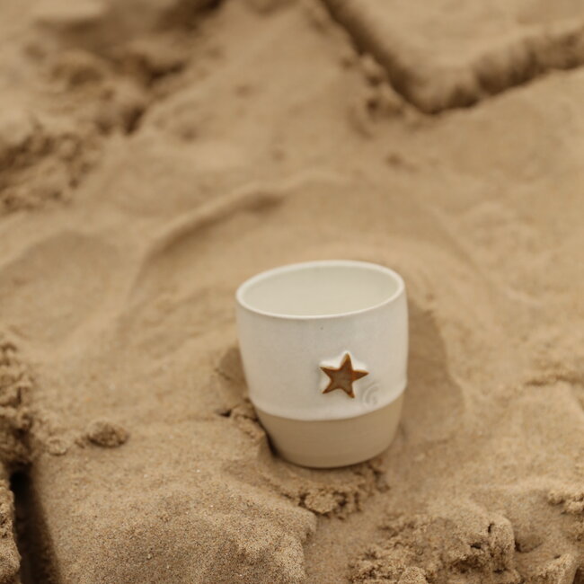 White handmade ceramic cup from the “White Star” service with a mustard-colored sea star