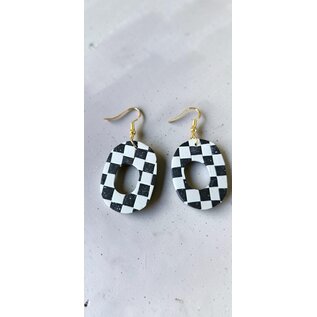 Handcrafted clay drop earrings with a black and white checkerboard pattern.