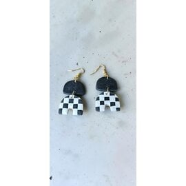 Handcrafted clay drop earrings with a black and white checkerboard pattern.