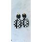 Handcrafted clay drop earrings with a black and white checkerboard pattern.