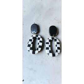Handcrafted clay drop earrings with a black and white checkerboard pattern.
