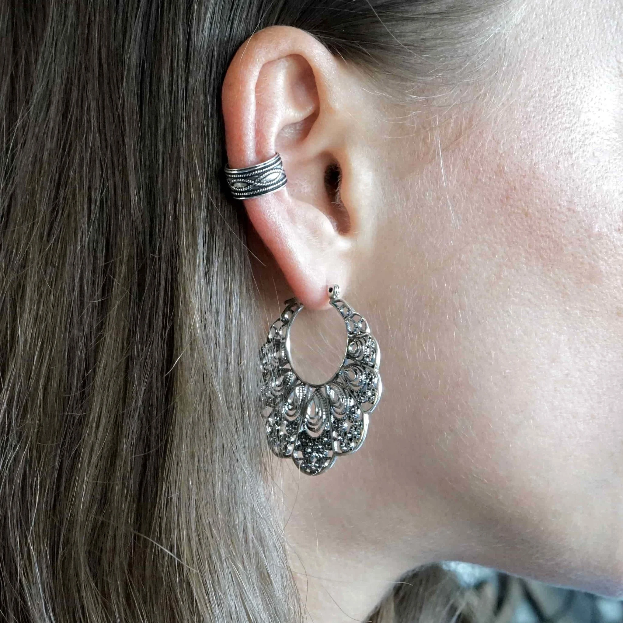 Zilveren ear cuff gecombineerd met oorhangers voor een gelaagde ear stack look