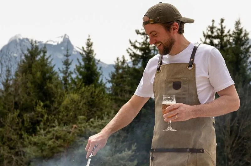 Een man barbecuet in een schort van Alaskan Maker