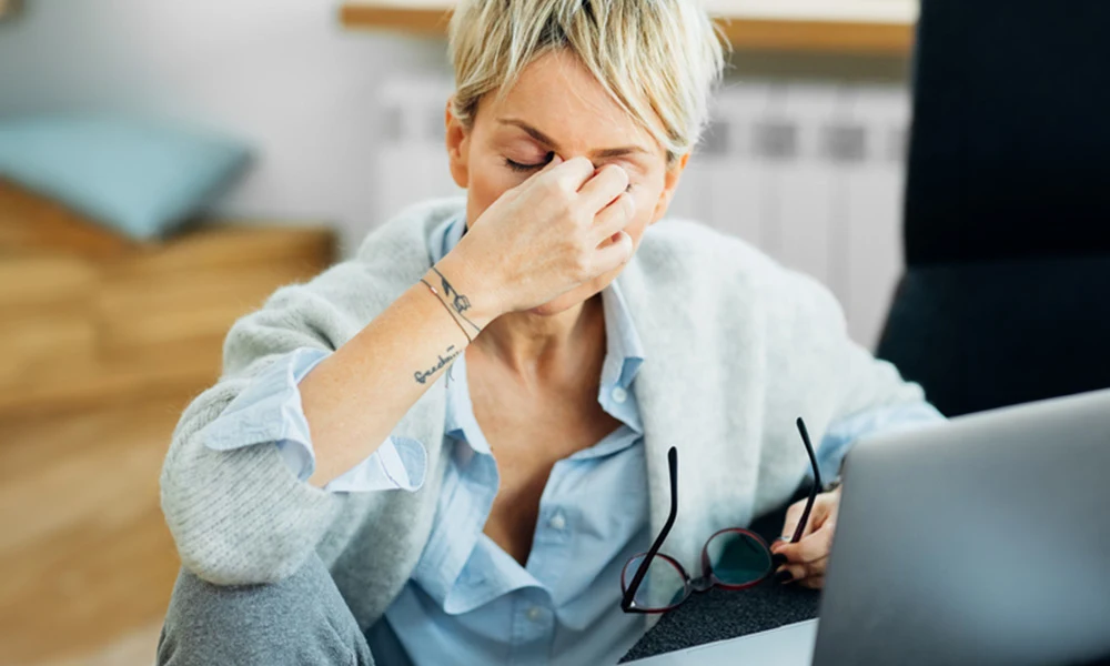 A woman with headache and eye pain from wearing glasses