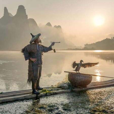 Smokes a pipe at the Li River