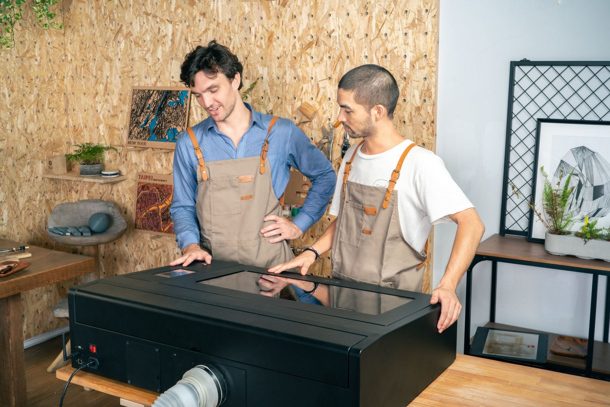 Two men working with a FLUX Beambox in a workshop setting.