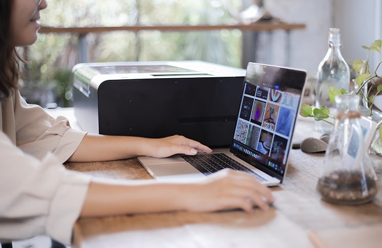 Close up of a women working on her laptop next to a FLUX Beamo