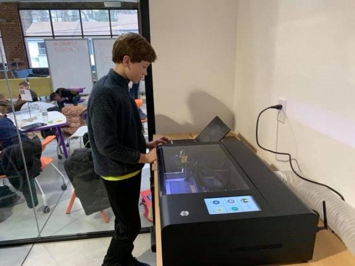 A boy working with a FLUX Beambox Pro laser cutter