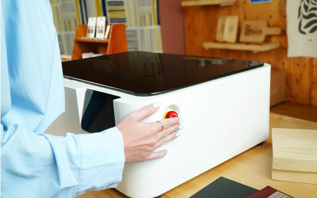 Female hand pressing the red emergy button on a FLUX Ador.