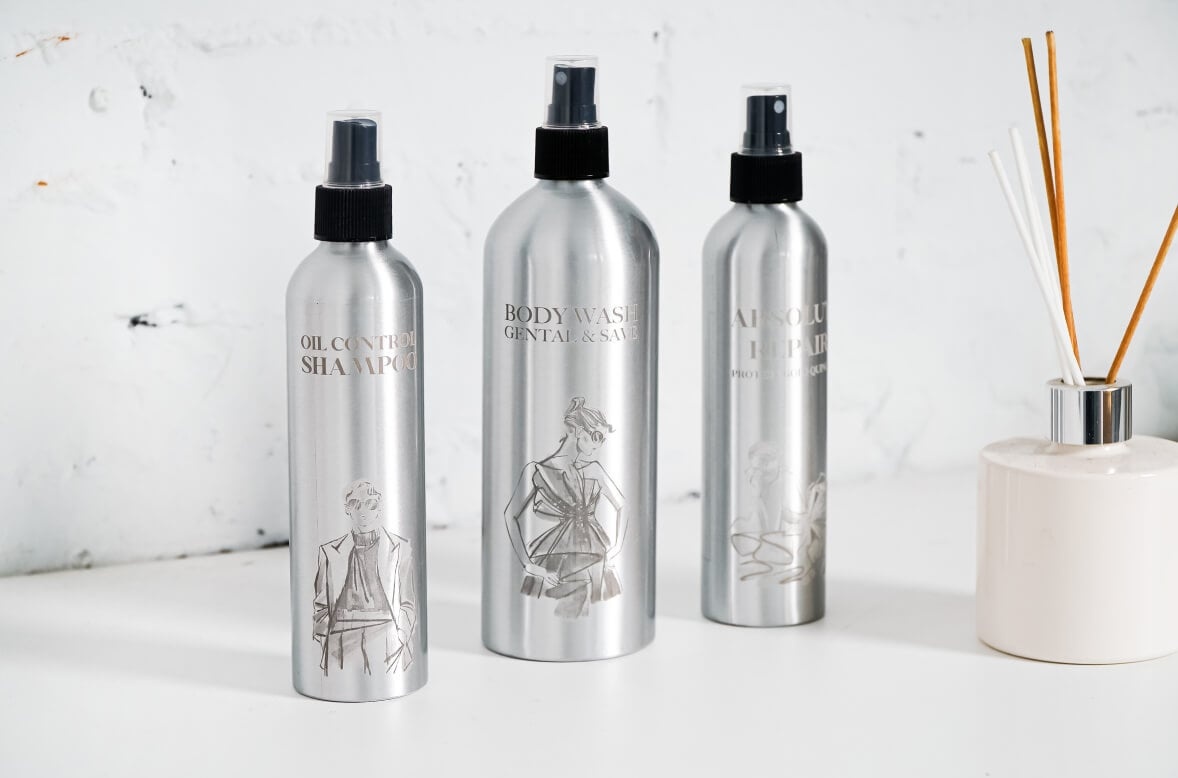 Three aluminium spray bottles with engraved designs by the FLUX Ador rotary module.