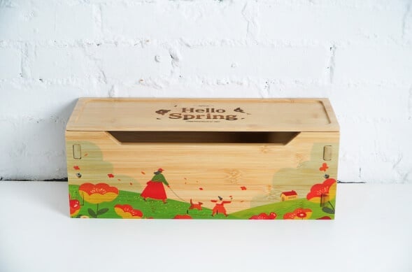 Wooden box with a colourful landscape printed on the front and an engraving of 'Hello Spring' on the lid.