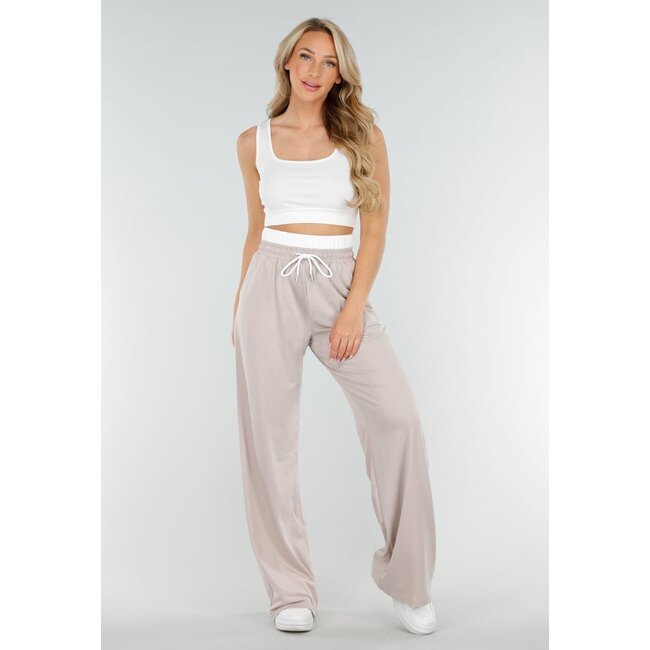 Weißes Crop-Top und beigefarbene weite Hose mit Gummizug in der Taille