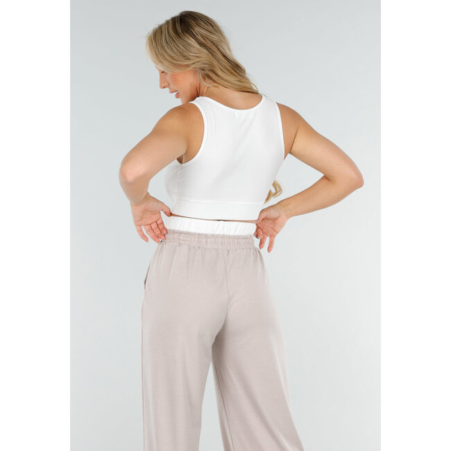 Weißes Crop-Top und beigefarbene weite Hose mit Gummizug in der Taille