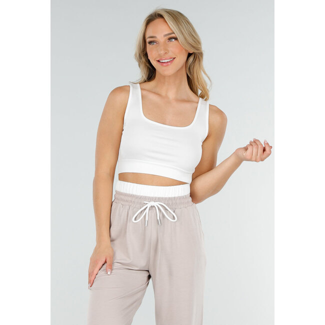 Weißes Crop-Top und beigefarbene weite Hose mit Gummizug in der Taille