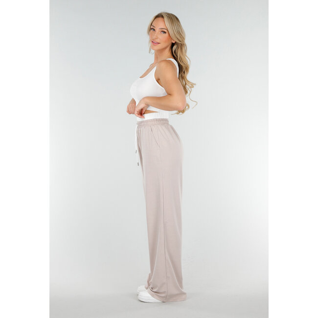 Weißes Crop-Top und beigefarbene weite Hose mit Gummizug in der Taille