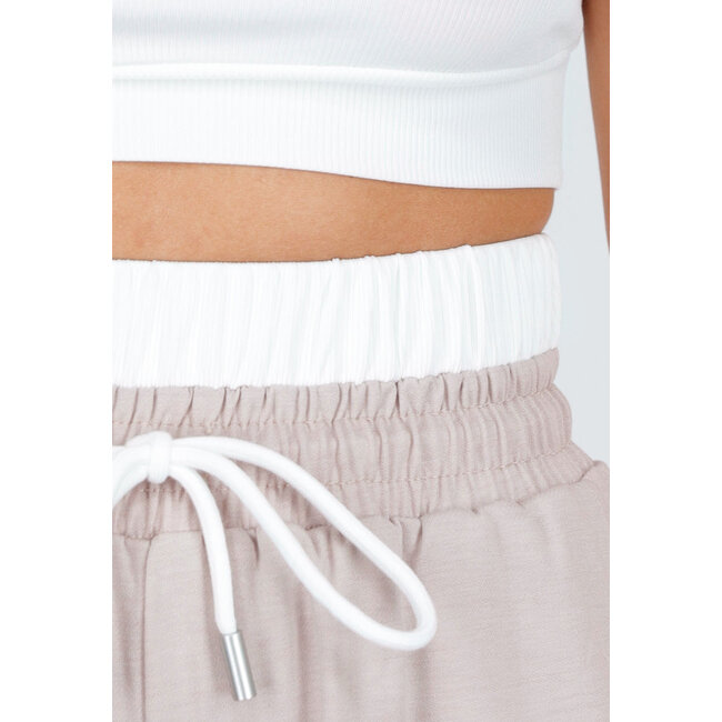 Weißes Crop-Top und beigefarbene weite Hose mit Gummizug in der Taille