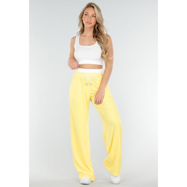 Weißes Crop-Top und buttergelbe weite Hose mit Gummizug am Bund