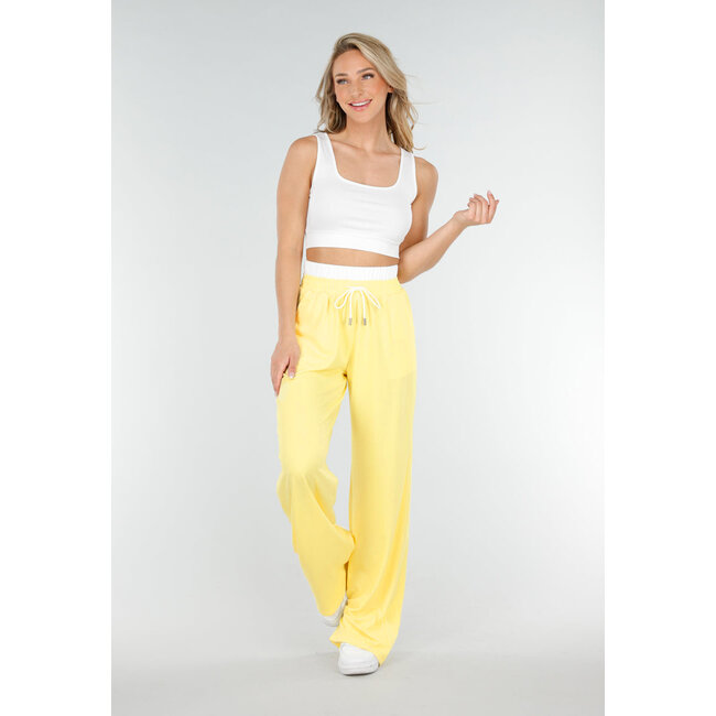Weißes Crop-Top und buttergelbe weite Hose mit Gummizug am Bund
