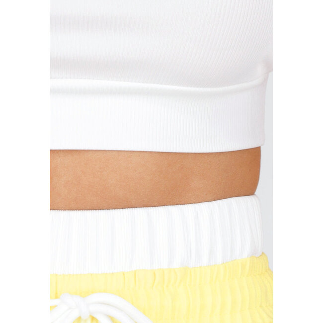 Weißes Crop-Top und buttergelbe weite Hose mit Gummizug am Bund