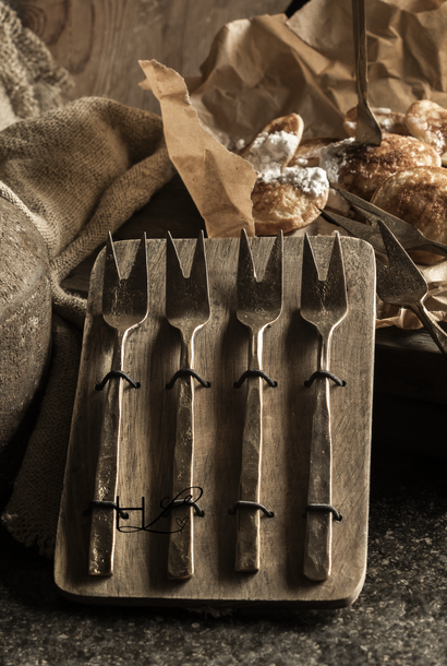 Geschenkset mit Löffeln, Gabeln oder Käsebesteck auf einem Holzteller