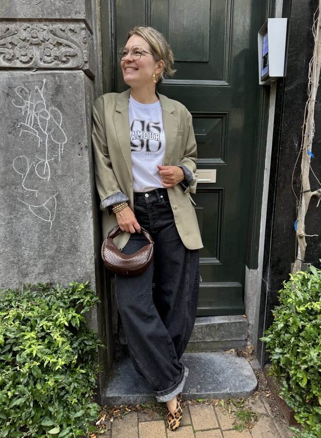 Midlife woman wearing a pale khaki blazer, graphic tee and dark jeans