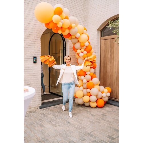 Grote ballonpilaar in oranje tinten bij een winkelopening