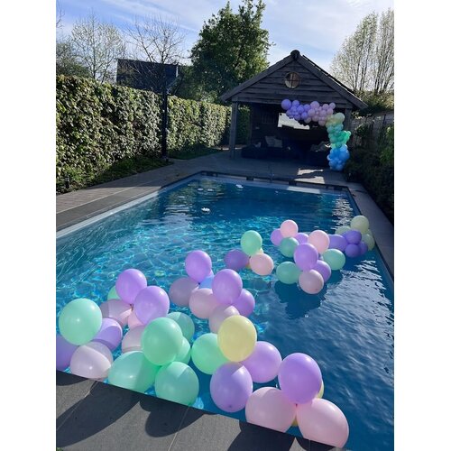 Pastelkleurige ballonnen drijvend in een zwembad