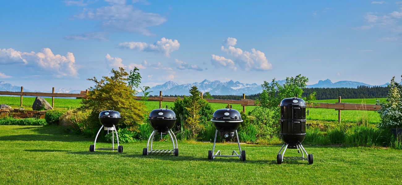 Vier zwarte Rösle barbecue-toestellen in een tuin