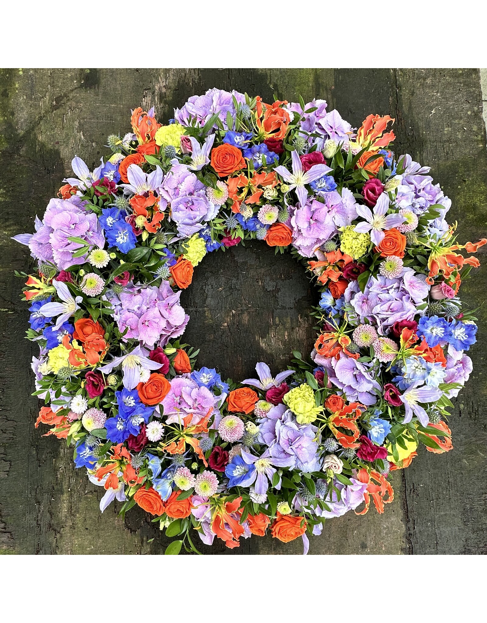 rouwkrans volledig uitgewerkt met veel bloemen in kleur naar keuze