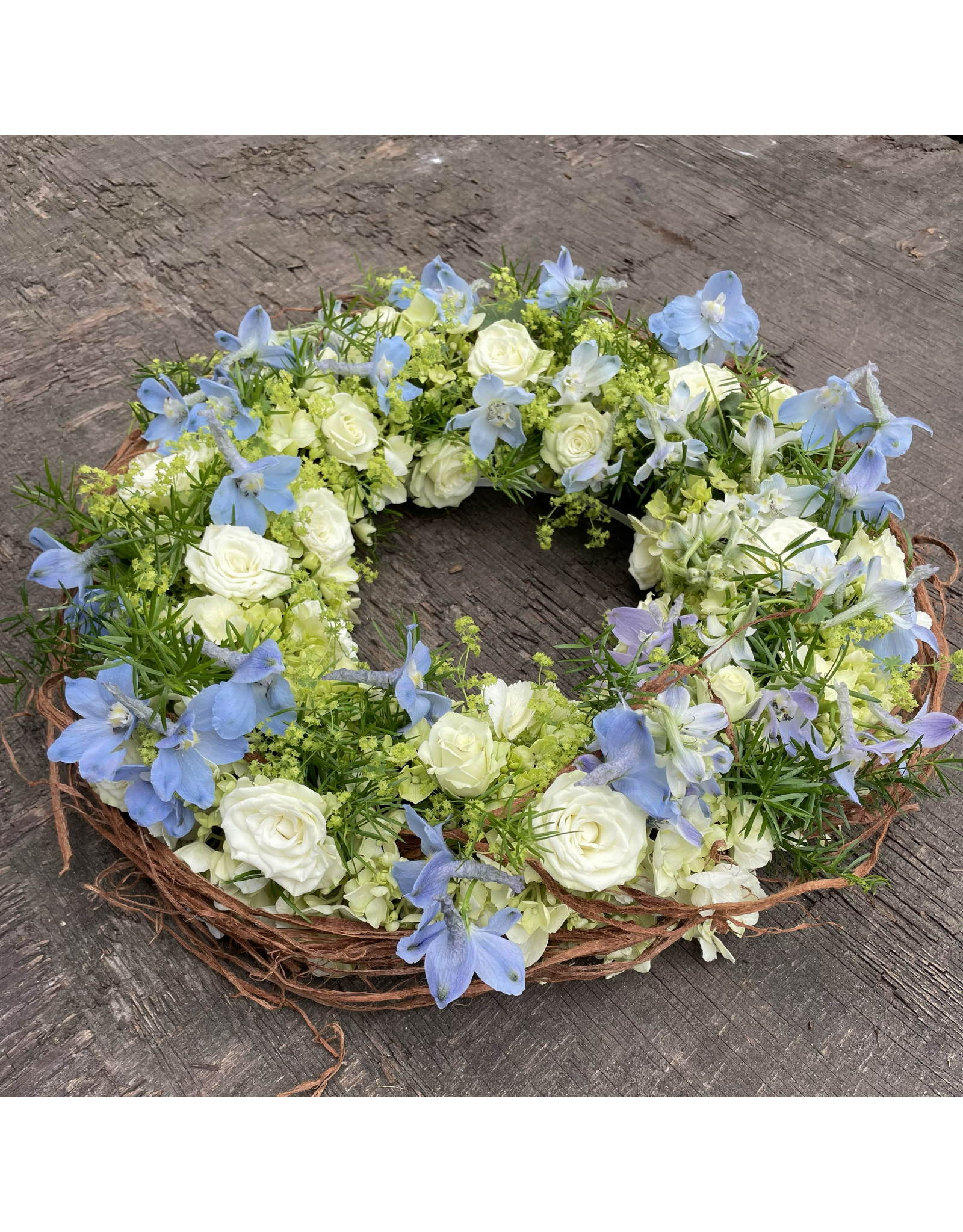 rouwkrans uitgewerkt met roosjes en velbloemen in  beschikbare kleur