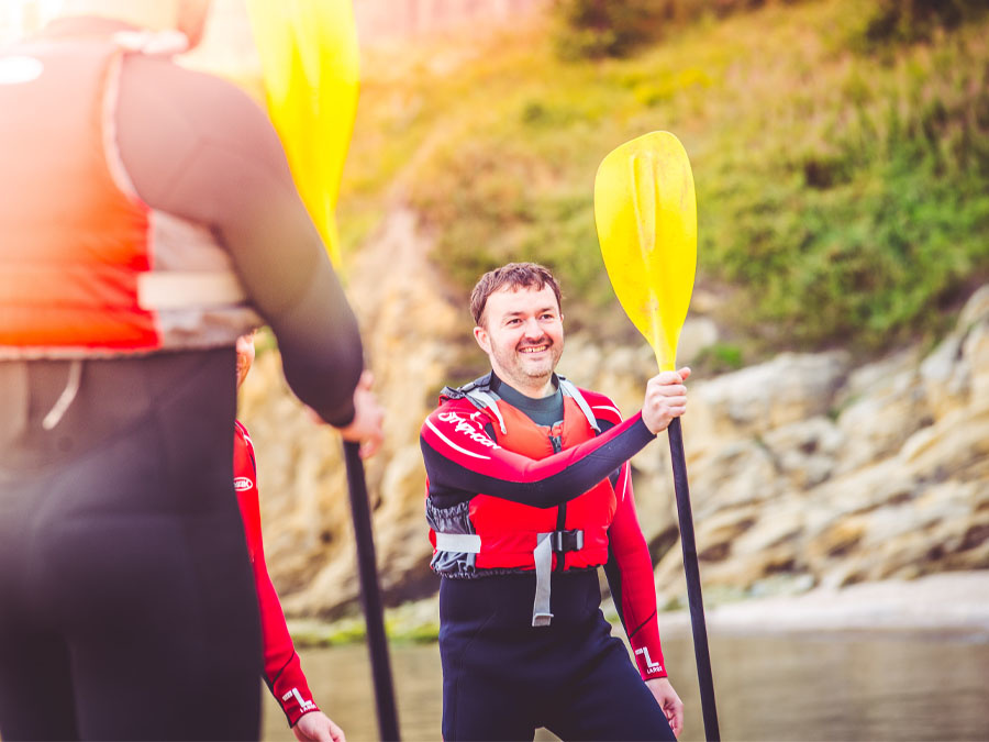 Man holding a kayak paddle in Cullercoats Bay