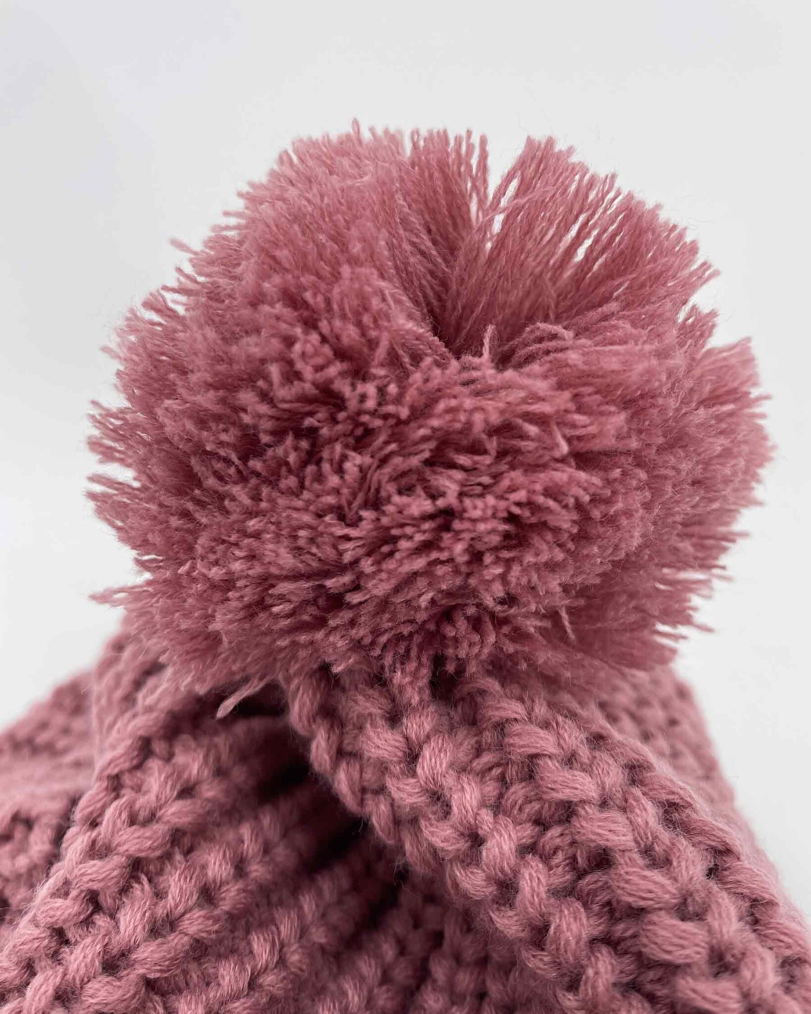 Heavy knitted pom pom beanie made from sustainable Polylana® fiber mix with trademark logo