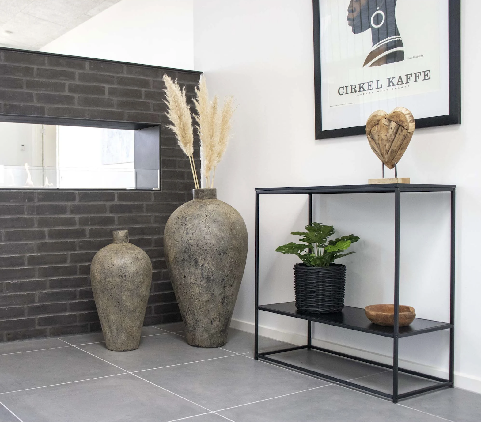 Industriële haltafel met zwart metalen frame en houten blad, gecombineerd met grote vazen en een moderne wanddecoratie.