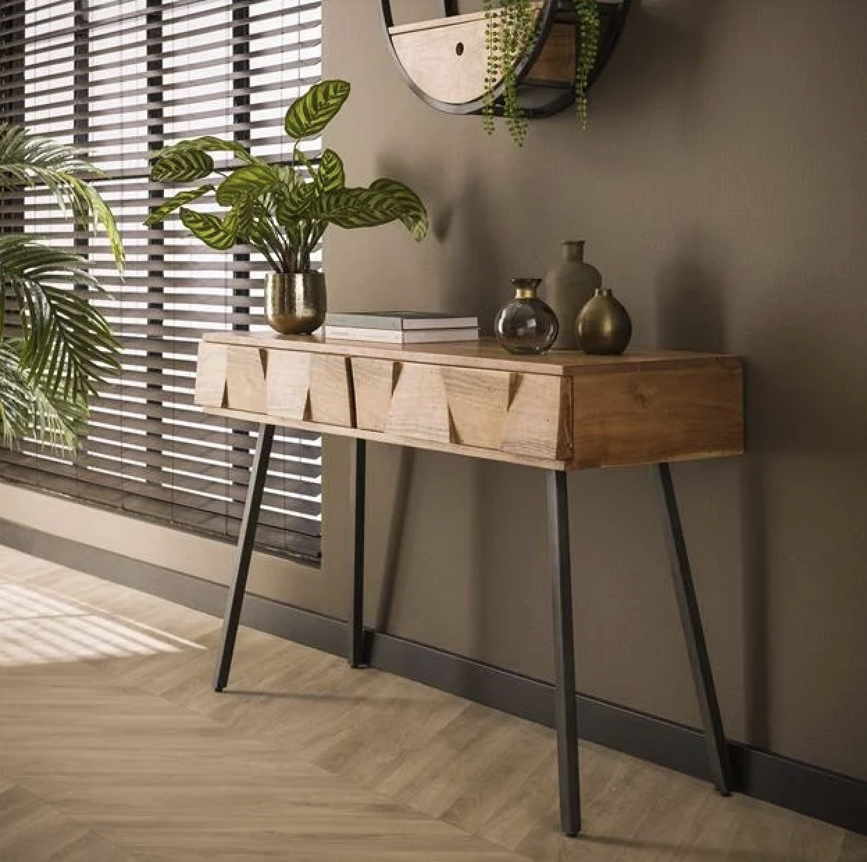 Haltafel van acaciahout met zwart metalen poten, gestyled met planten en gouden accessoires voor een warme uitstraling.