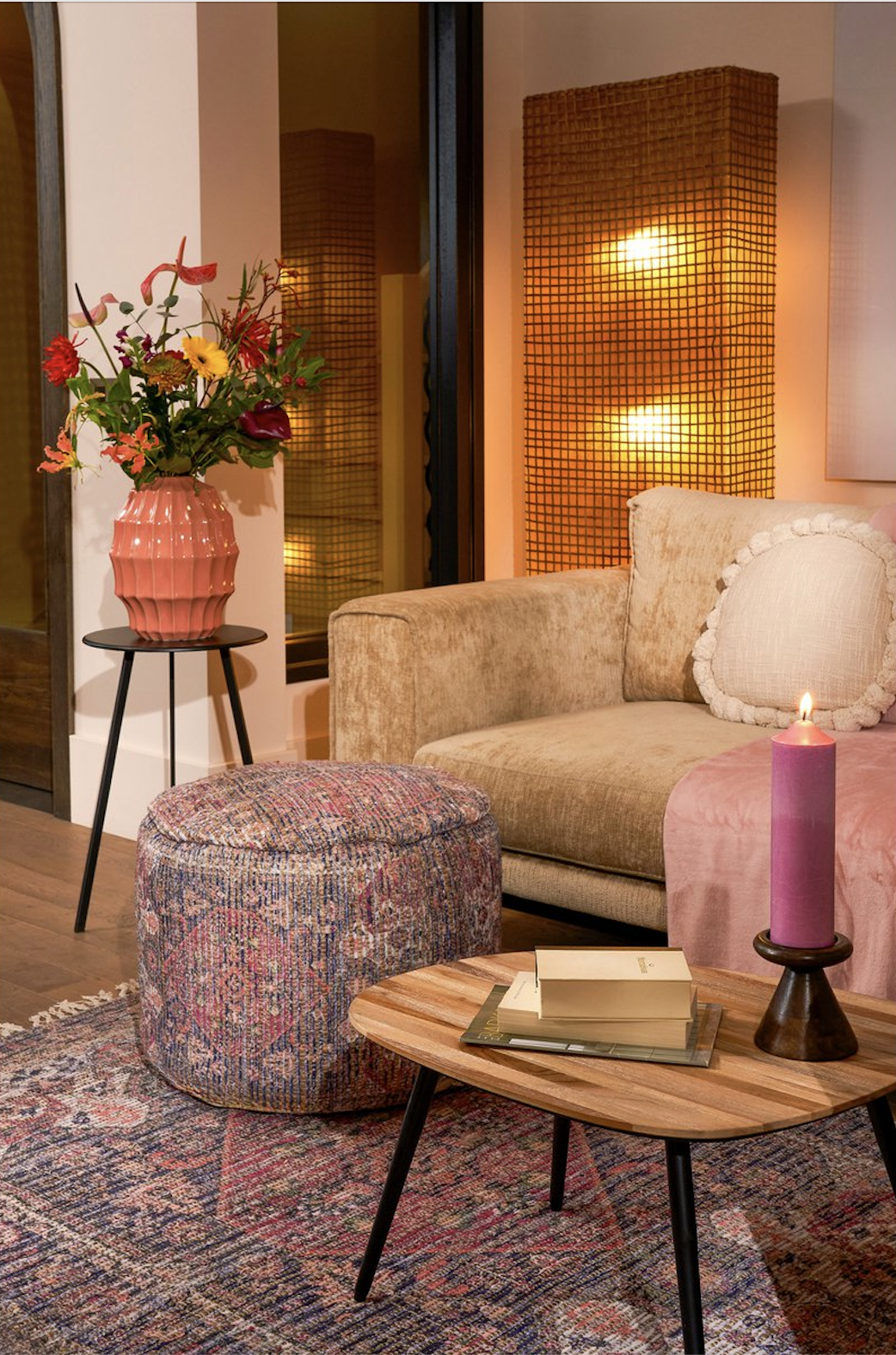 Warme zithoek met poef, plaid, bloemen en kaarslicht