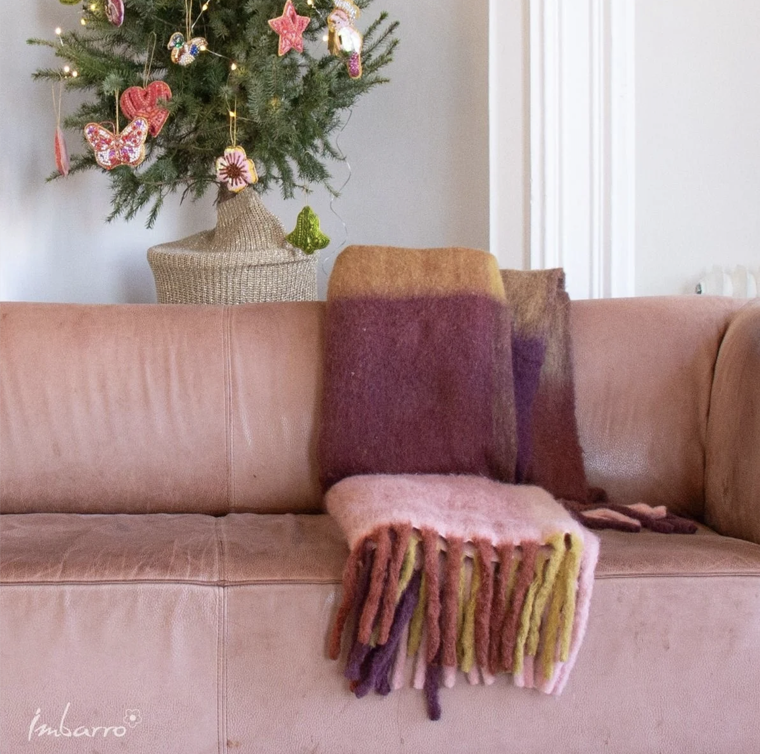 Zachte plaid in roze-aubergine tinten over bank – warme wintercombinatie in stijlvol interieur.