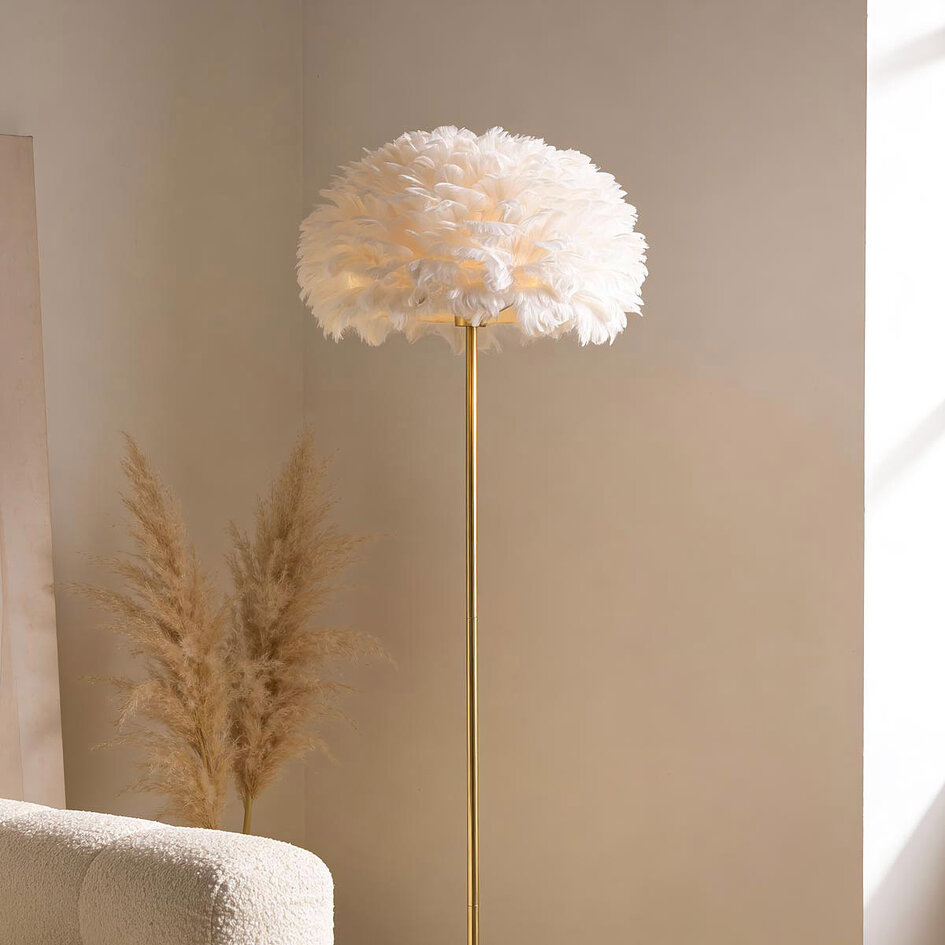 Designad golvlampa Evania med vita fjädrar och fot i guldmässing