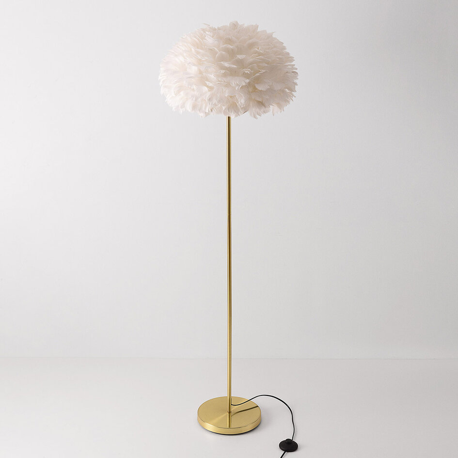 Designad golvlampa Evania med vita fjädrar och fot i guldmässing