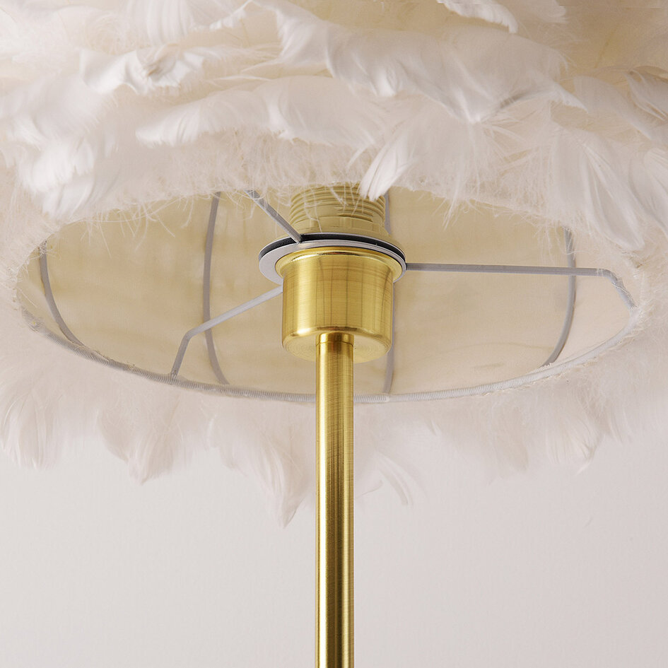 Designad golvlampa Evania med vita fjädrar och fot i guldmässing