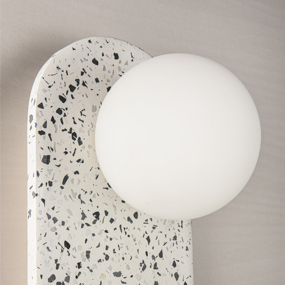 Vägglampa Velo av cement och mjölkvitt glas i terrazzolook