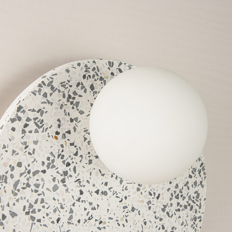 Rund vägglampa Velo av cement och mjölkvitt glas i terrazzolook
